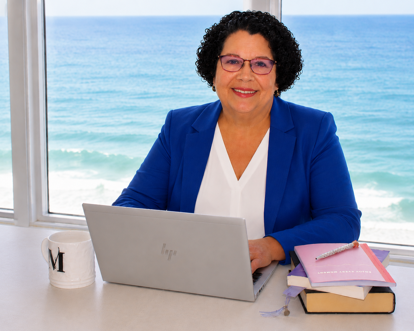 Martha Thorne Reed, author of The Day Hope Walked Five Miles, smiling at her desk with an ocean view